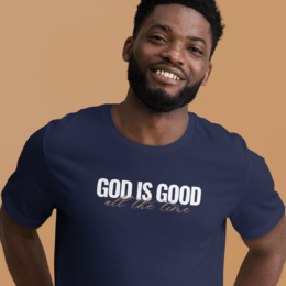Person wearing navy God Is Good Tee with white lettering and gold script detail