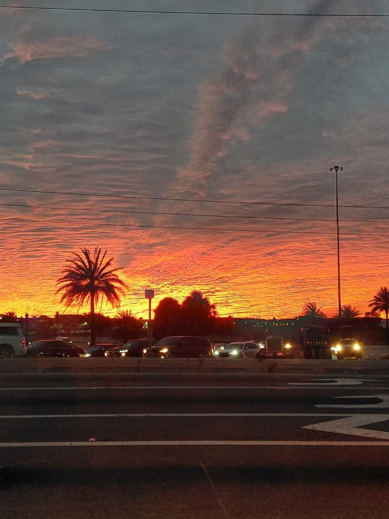 Orange sunset beneath rippled clouds over palm trees and traffic in Davenport, Florida