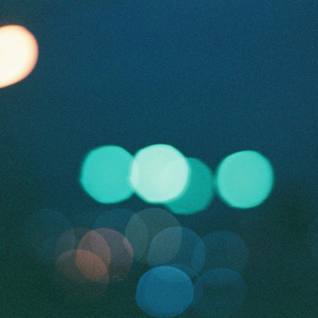 Blurred colorful bokeh lights create an abstract pattern in a dark blue night setting.